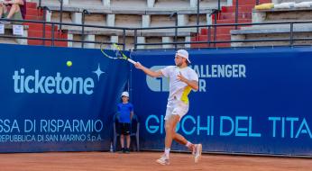 Giocatore di tennis colpisce la palla su un campo in terra battuta.