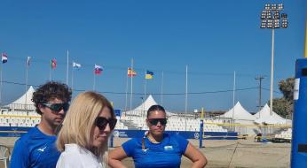 Tre persone discutono su un campo da beach volley.