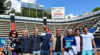 Gruppo di persone su un campo da tennis con un trofeo.